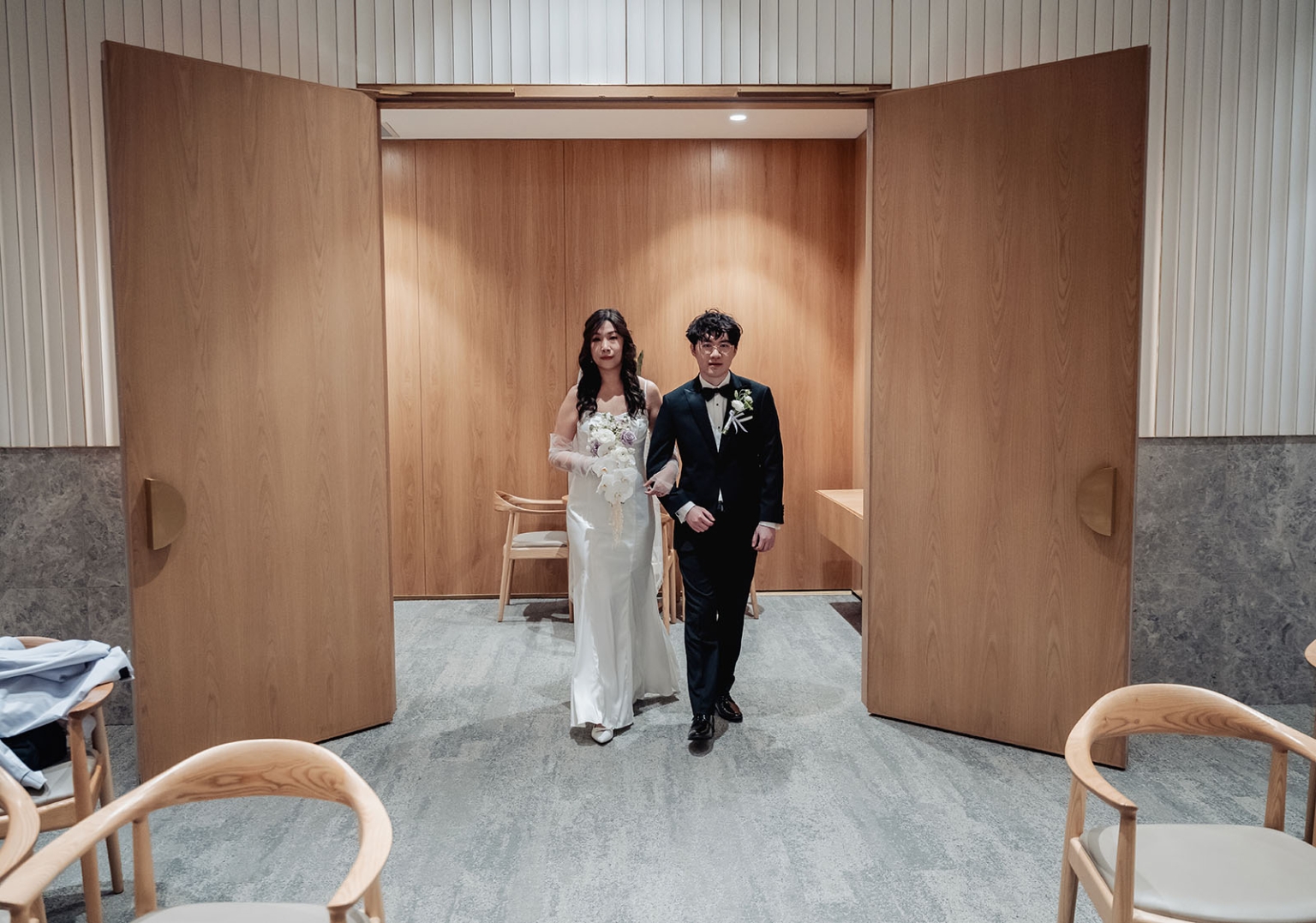 marriage rego office wedding – teri & thomas 1 Teri and Thomas entering the ceremony room arm in arm, dressed in a white wedding gown and black tuxedo.
