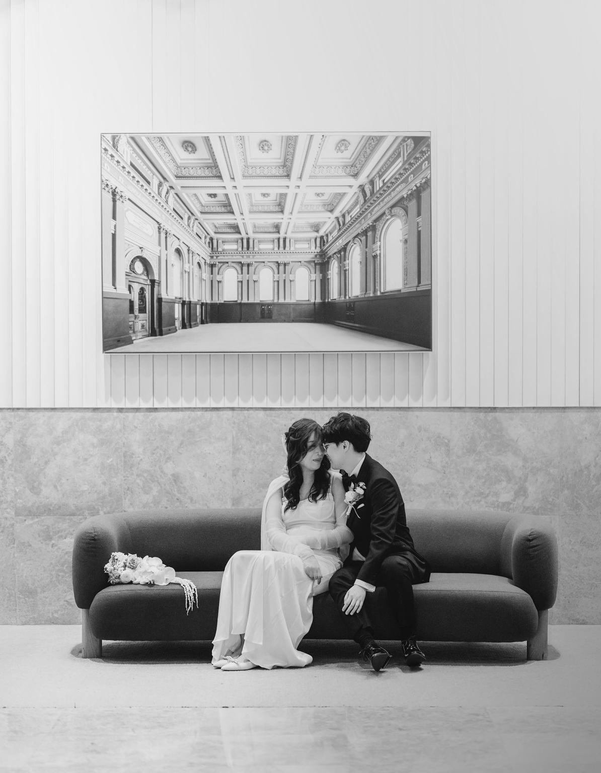 marriage rego office wedding – teri & thomas 11 Teri and Thomas seated closely on a sofa after their Adelaide Marriage Registration Office wedding ceremony, with a bouquet beside them