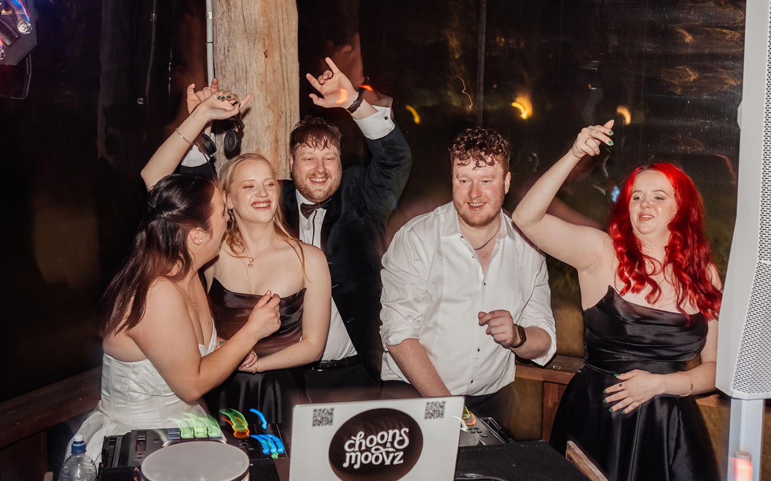 Wedding guests dancing and raising their hands around a DJ booth during the reception at Barristers Block