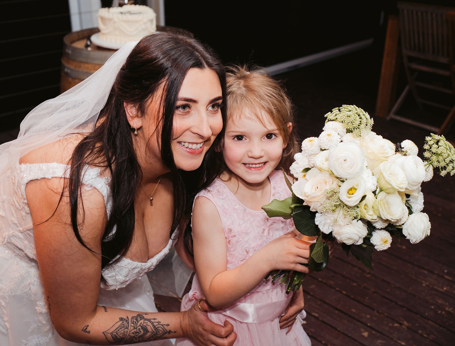 beach road winery wedding – alysha & nik 51 Bride Alysha crouches beside a young flower girl holding a white wedding bouquet at Beach Road Winery.