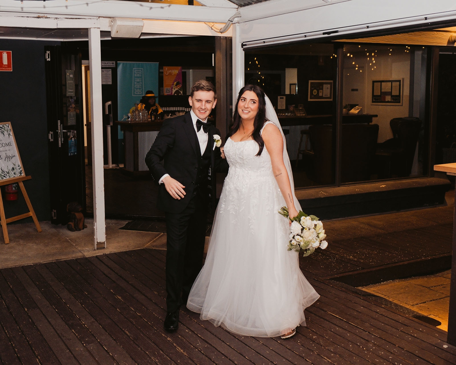 beach road winery wedding – alysha & nik 49 Alysha and Nik in wedding attire at the entrance to Beach Road Winery, with Alysha holding a white bouquet.