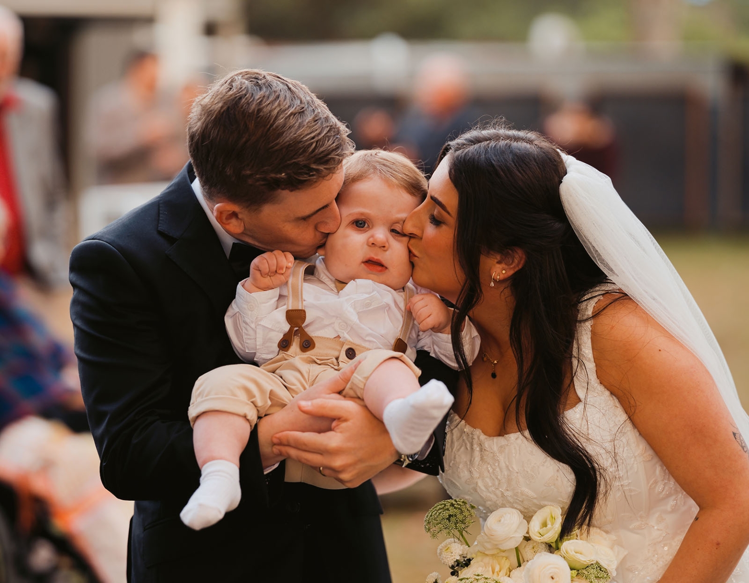 beach road winery wedding – alysha & nik 30 Alysha and Nik in wedding attire kissing a baby they are holding together