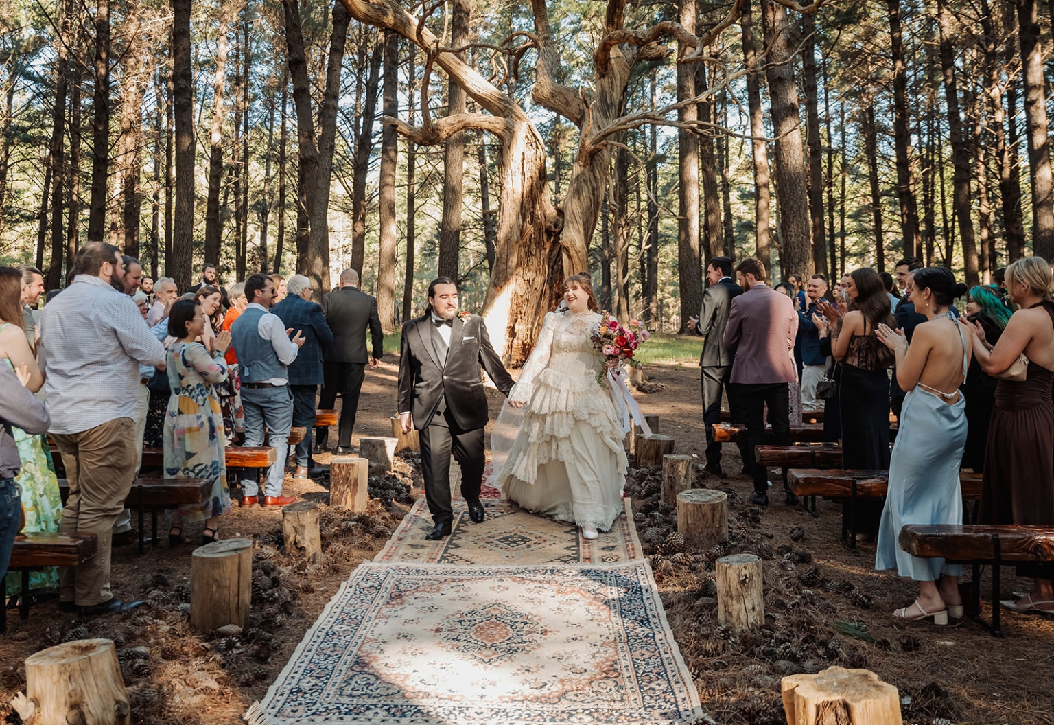 burbrook wedding – amber & angus | kuitpo forest wedding 33 Amber and Angus walk down the aisle after their forest wedding ceremony as guests applaud among tall trees.