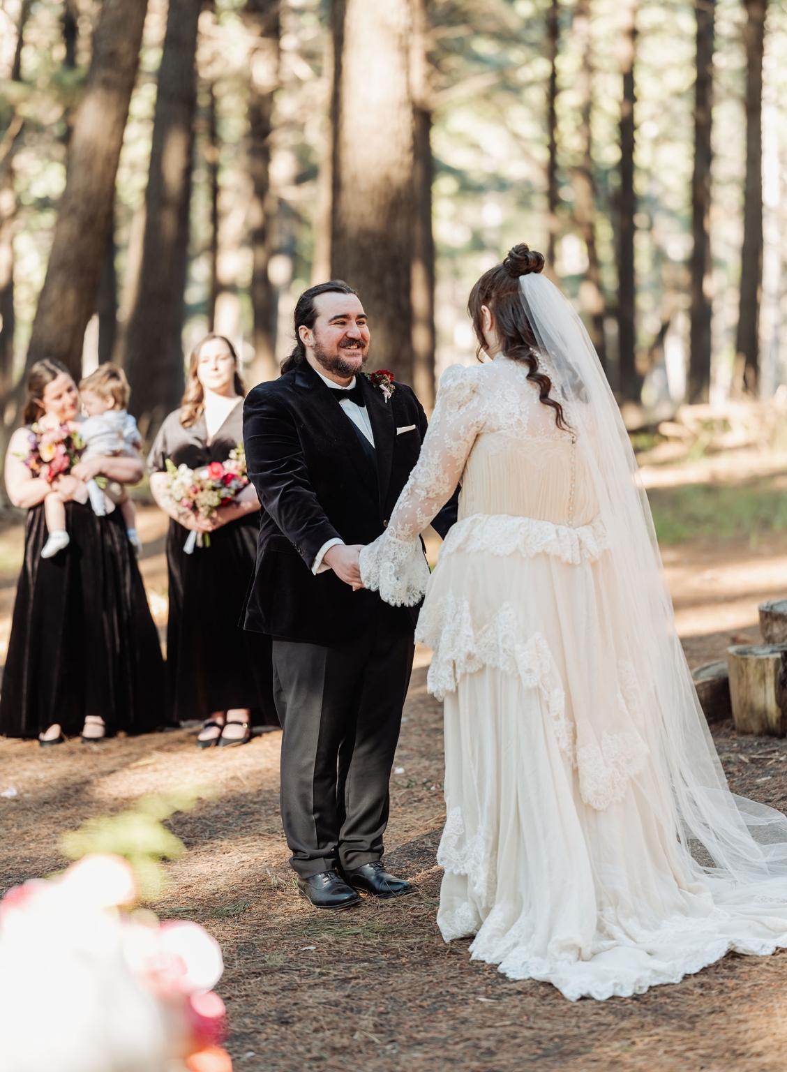 burbrook wedding – amber & angus | kuitpo forest wedding 29 Angus holding hands with Amber during their forest wedding ceremony, with bridesmaids standing behind them
