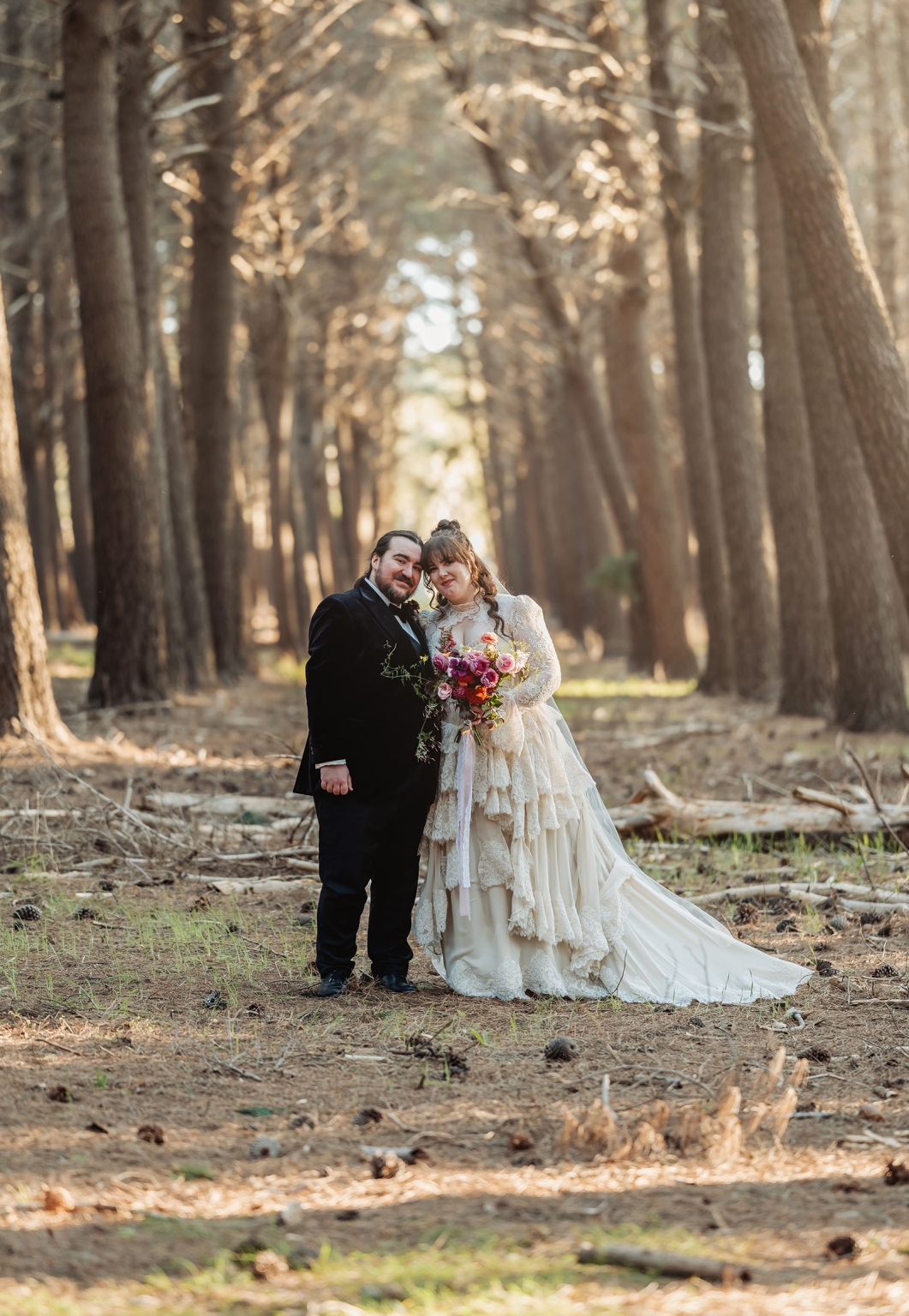 burbrook wedding – amber & angus | kuitpo forest wedding 44 Amber and Angus standing together among tall trees in Kuitpo Forest, with Amber holding a colourful bouquet.