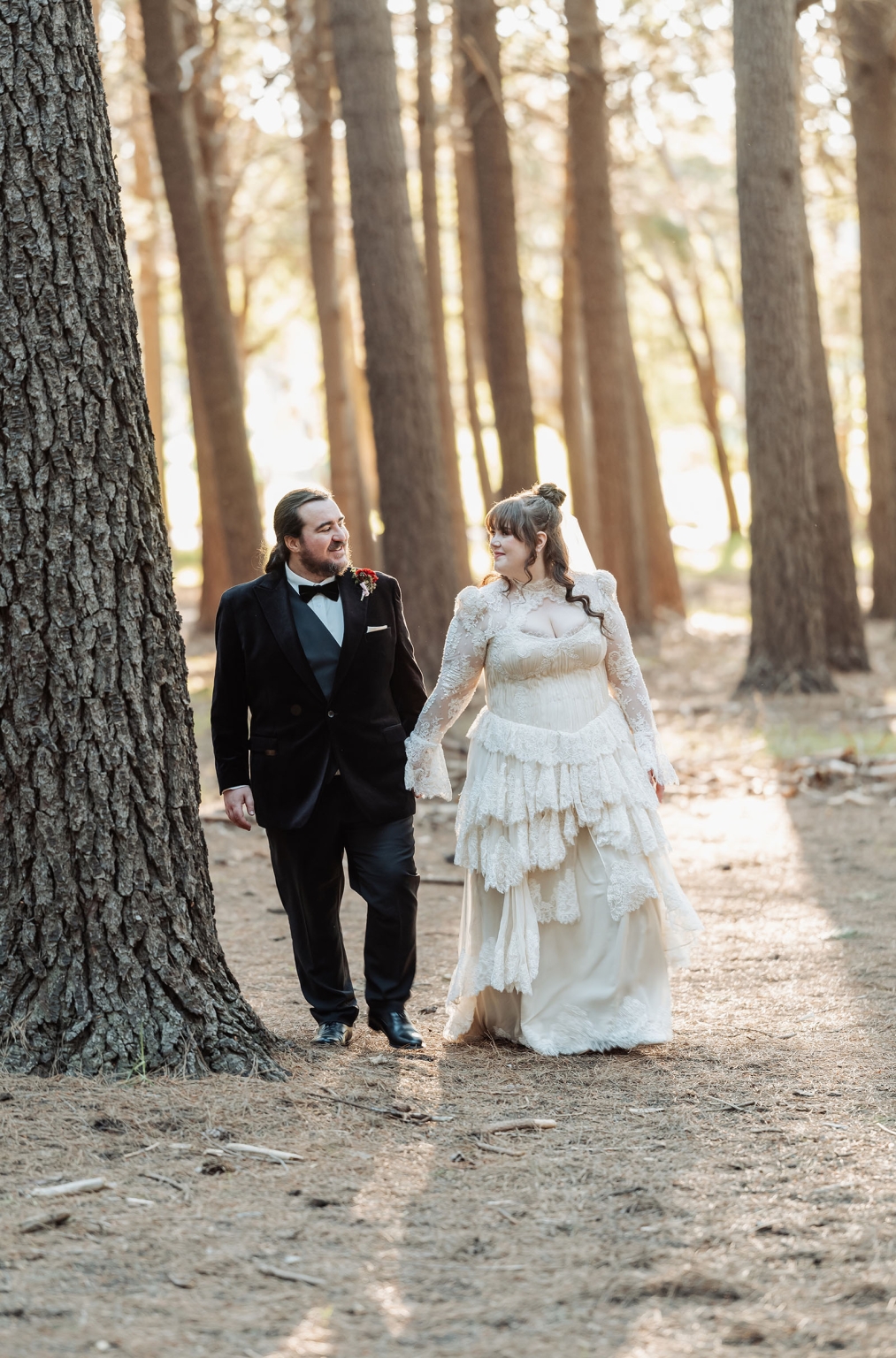 burbrook wedding – amber & angus | kuitpo forest wedding 39 Amber and Angus holding hands as they walk through sunlit pine trees in Kuitpo Forest
