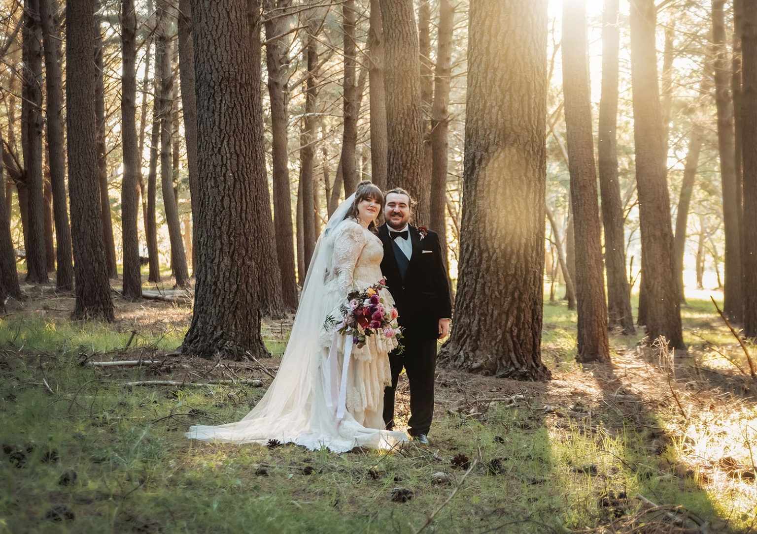 burbrook wedding – amber & angus | kuitpo forest wedding 42 Amber and Angus standing among tall pine trees in Kuitpo Forest, with warm sunlight behind them on their wedding day
