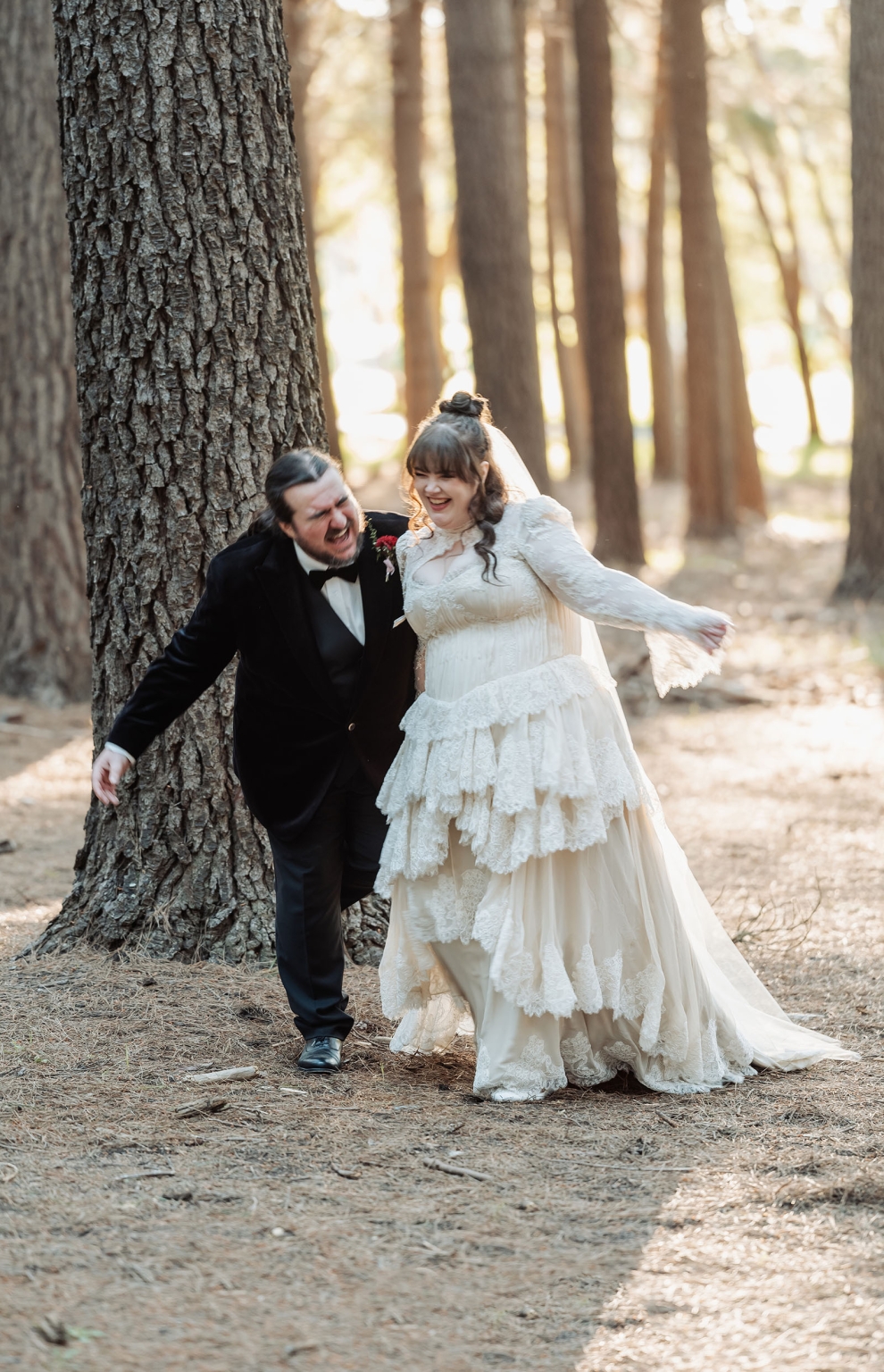 burbrook wedding – amber & angus | kuitpo forest wedding 40 Amber and Angus laughing beside a large tree in Kuitpo Forest, wearing their wedding attire.
