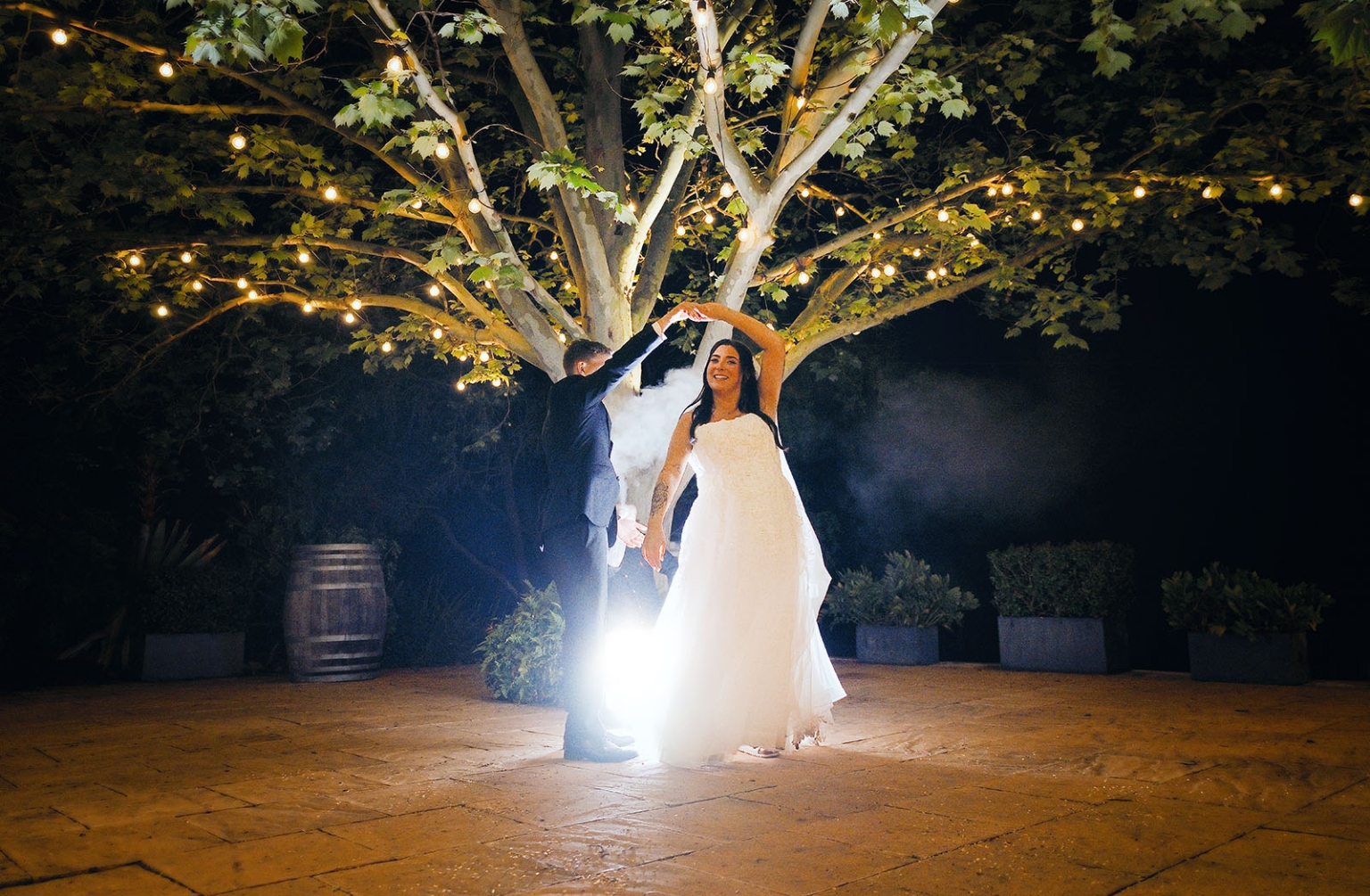 beach road winery wedding – alysha & nik 52 Bride in a white wedding dress dances beneath festoon lights with her partner at night at Beach Road Winery