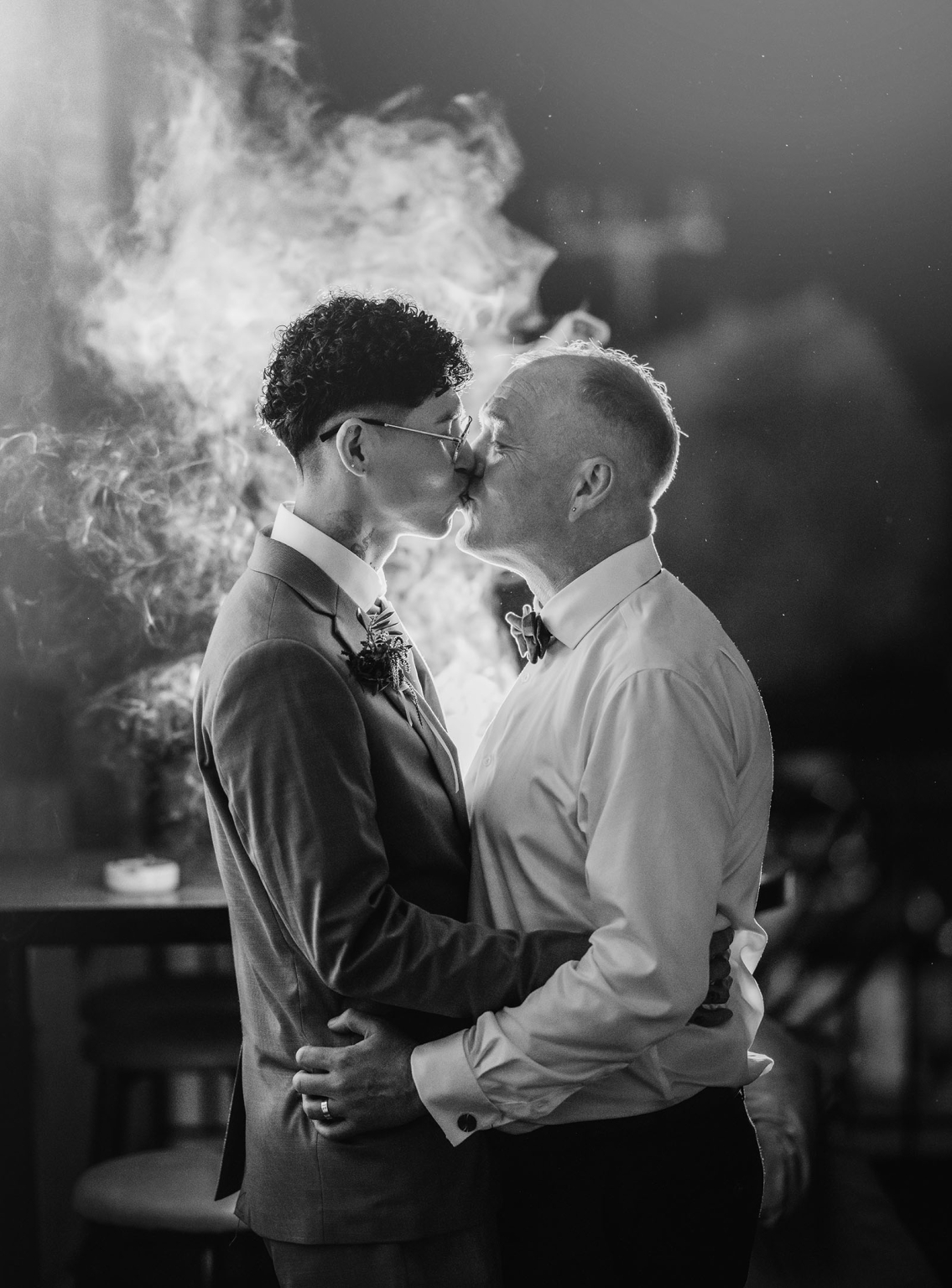 hotel royal wedding - brad & manuel 47 Brad and Manuel kissing in formal wedding attire, backlit by swirling smoke or firelight