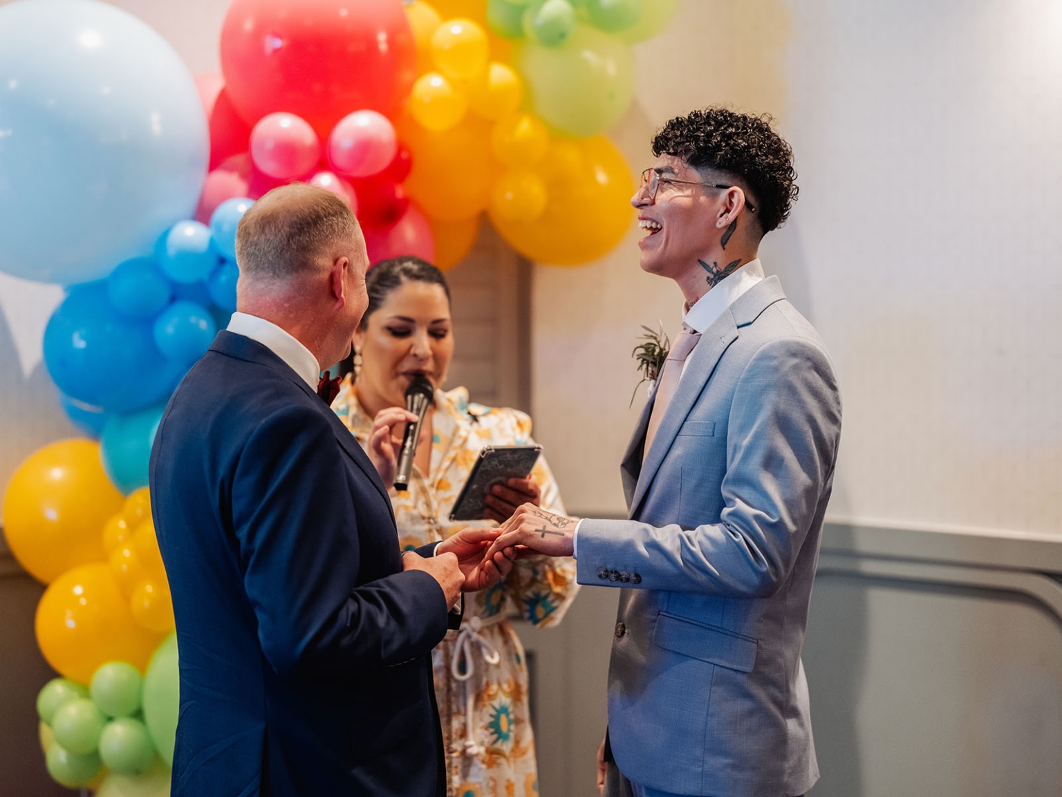 hotel royal wedding - brad & manuel 28 Brad and Manuel hold hands during their wedding ceremony beneath a rainbow balloon display at Hotel Royal.