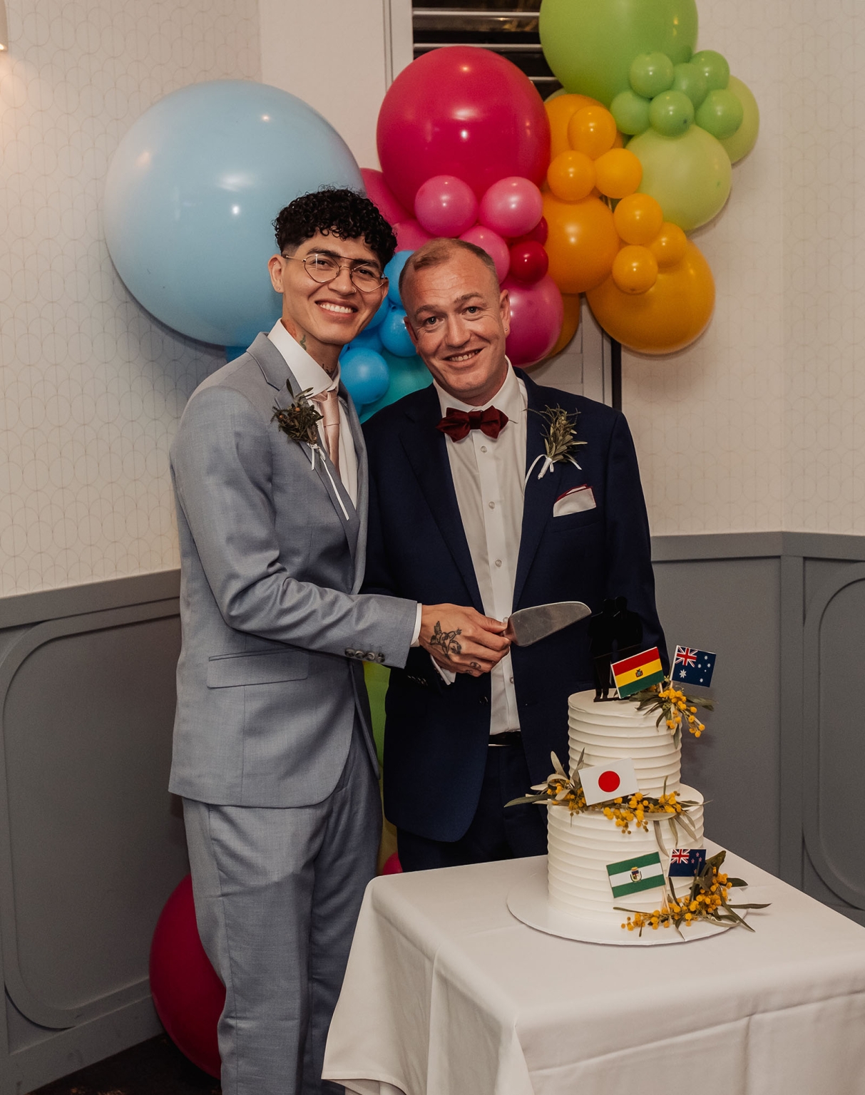 hotel royal wedding - brad & manuel 40 Brad and Manuel smiling as they cut their three-tier wedding cake beneath a colourful balloon display at Hotel Royal.