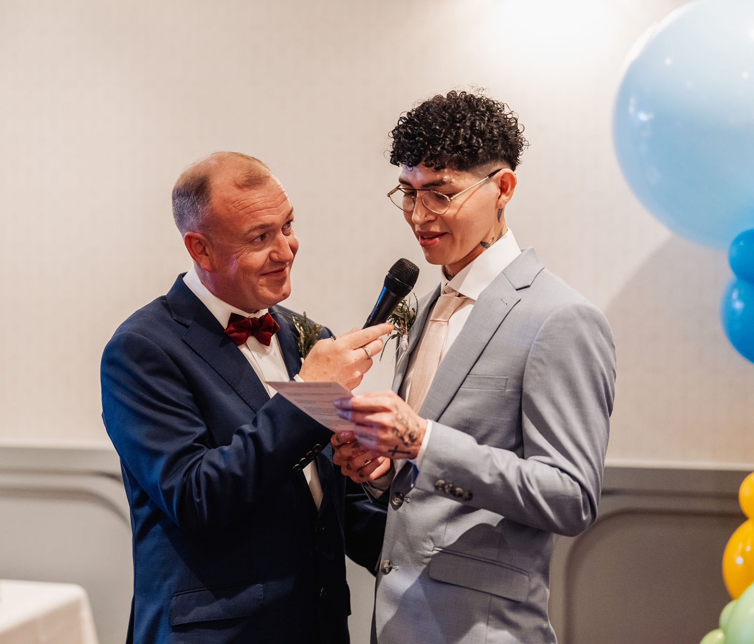 hotel royal wedding - brad & manuel 27 Brad and Manuel in suits reading from a card during their wedding reception, with blue balloons behind them