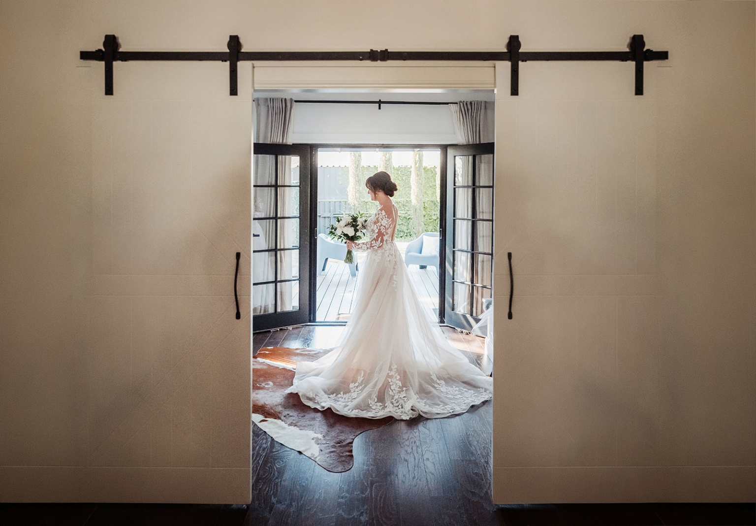serafino winery wedding – maor & sasha 22 Bride in a lace wedding dress holding a bouquet beside open French doors