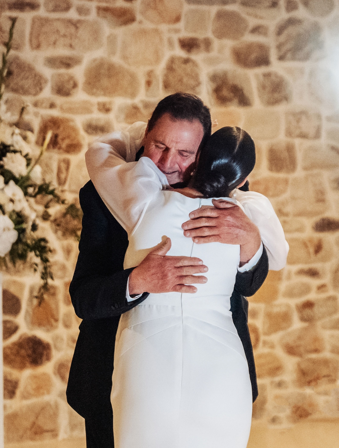 st joseph's chapel wedding – diana & michael 54 Bride in a white satin gown embracing a man in a dark suit against a stone wall at St Joseph's Chapel
