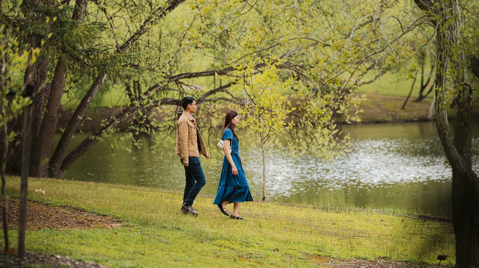 mt lofty botanic park proposal – watay & phouthun 1 Watay and Phouthun walking beside a lake beneath leafy trees at Mount Lofty Botanic Garden