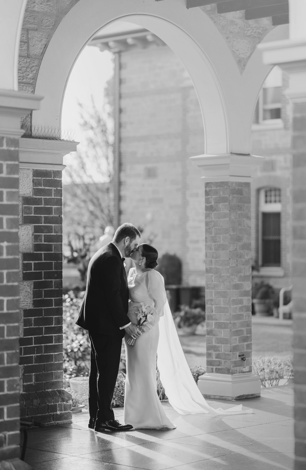 st joseph's chapel wedding – diana & michael 23 Diana and Michael kissing beneath the brick and stone archways at St Joseph's Chapel in Kensington