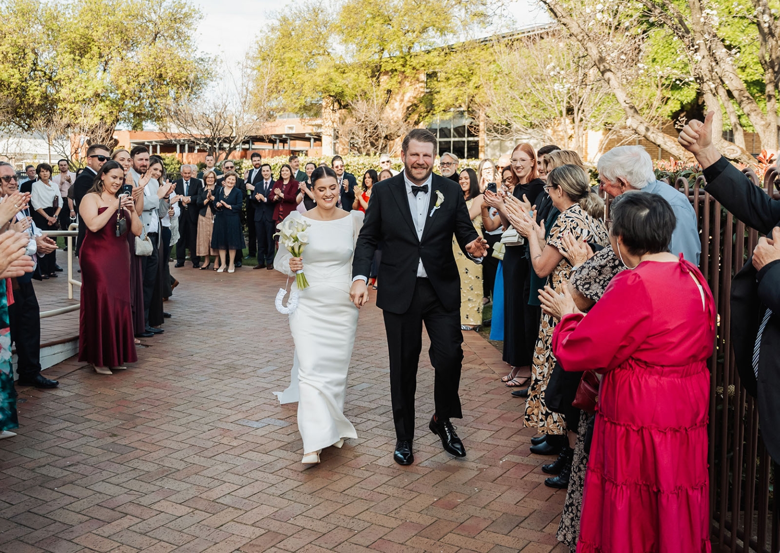 st joseph's chapel wedding – diana & michael 19 Diana and Michael walk hand in hand through applauding wedding guests after their chapel ceremony.