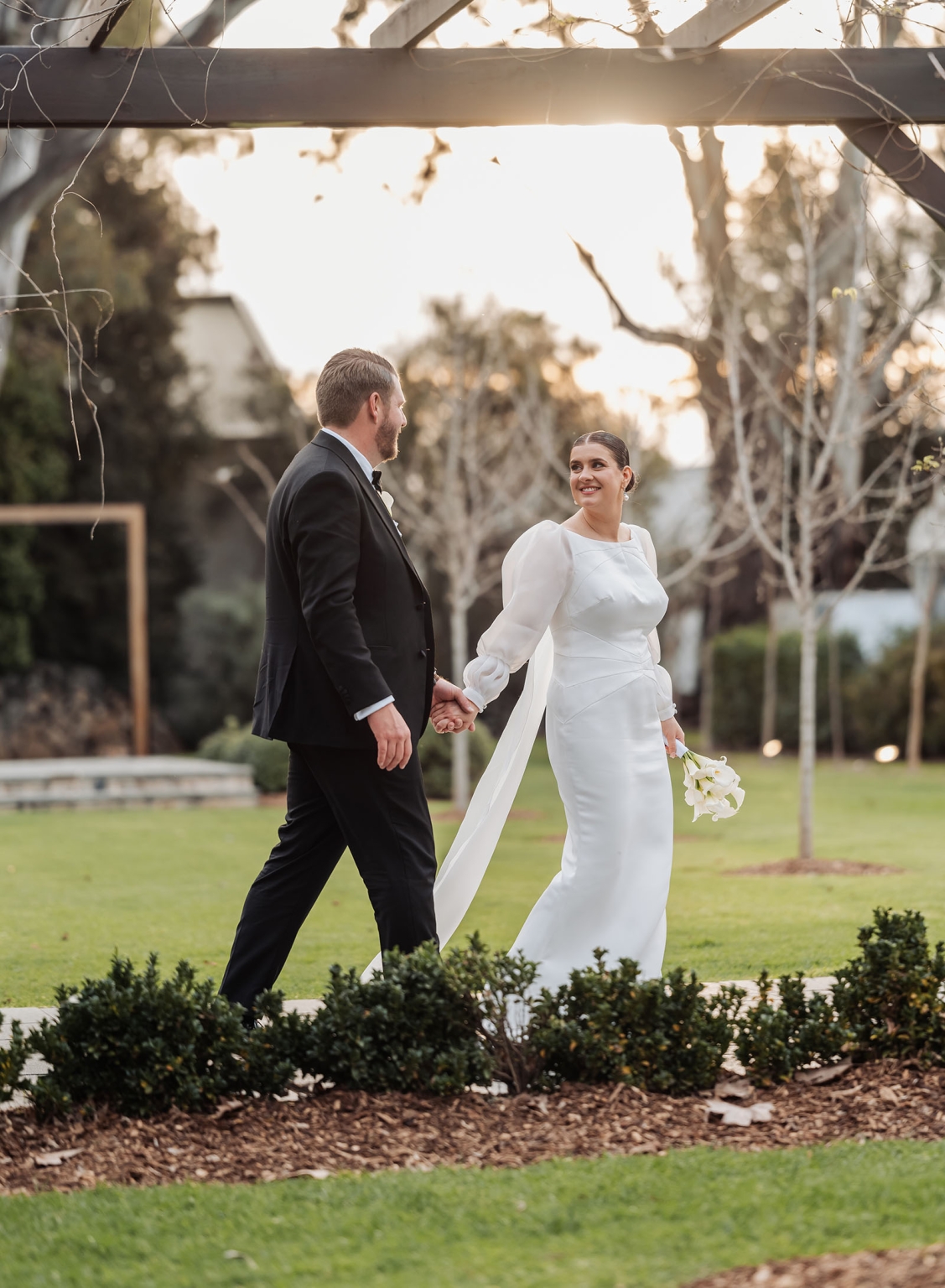 st joseph's chapel wedding – diana & michael 36 Diana and Michael walking hand in hand through a garden, with Diana holding a white bouquet