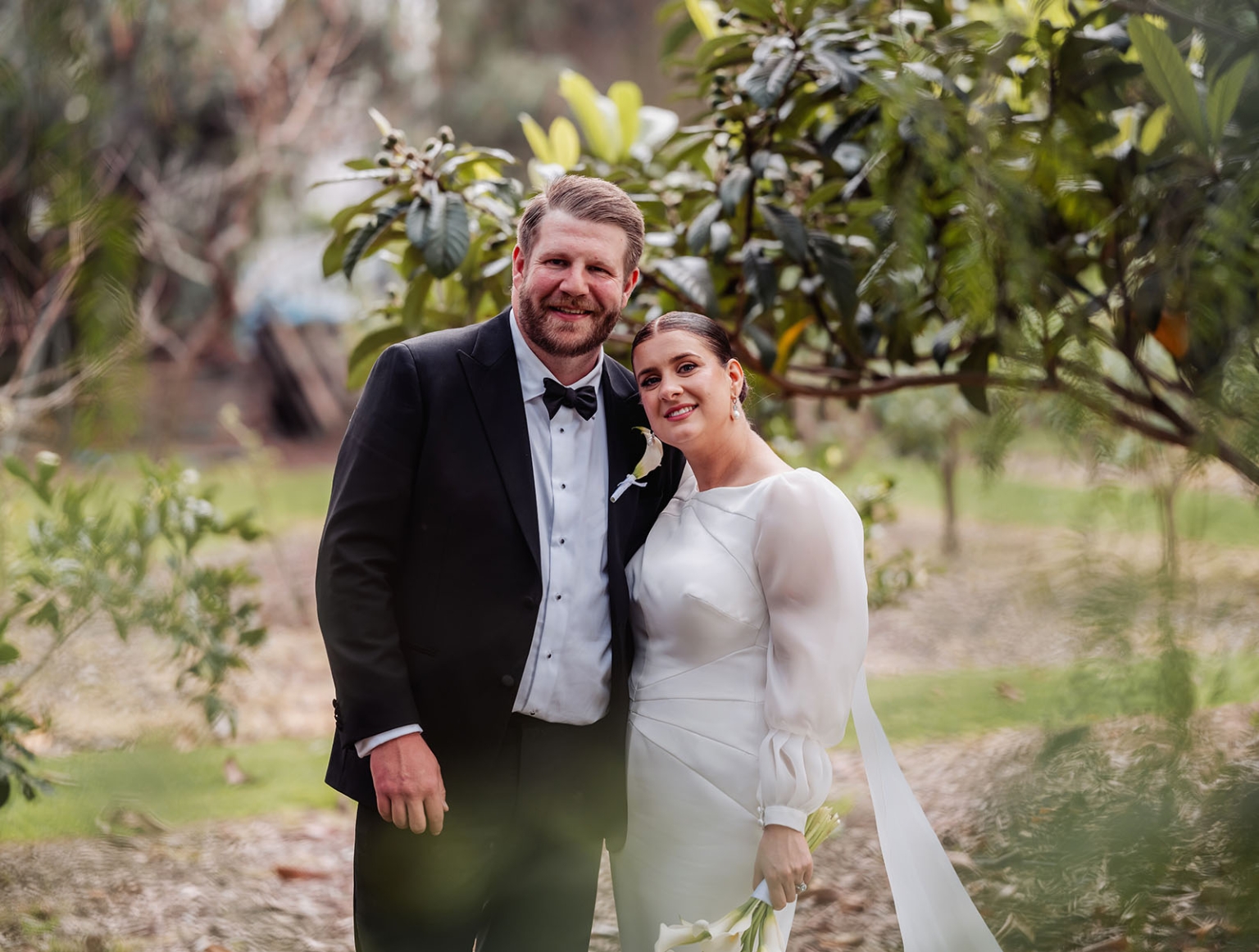 st joseph's chapel wedding – diana & michael 38 Diana and Michael smiling together in formal wedding attire among leafy garden plants