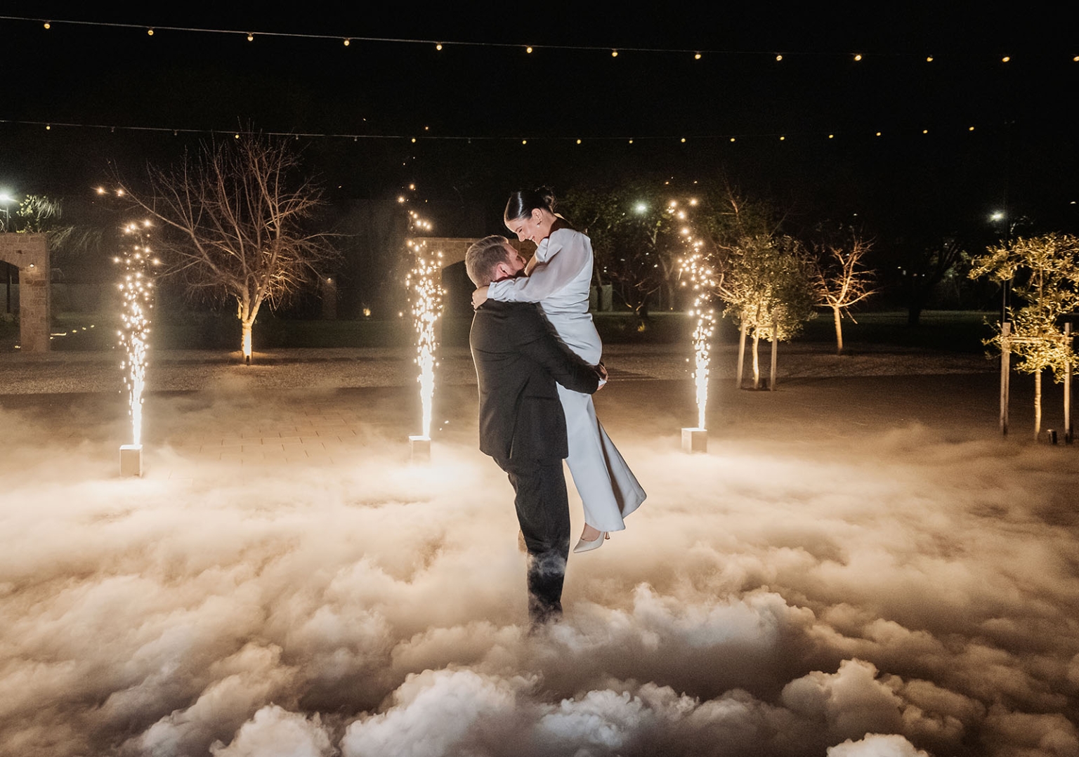 st joseph's chapel wedding – diana & michael 58 Diana and Michael embrace during their night-time wedding dance amid low fog, spark fountains and festoon lights.