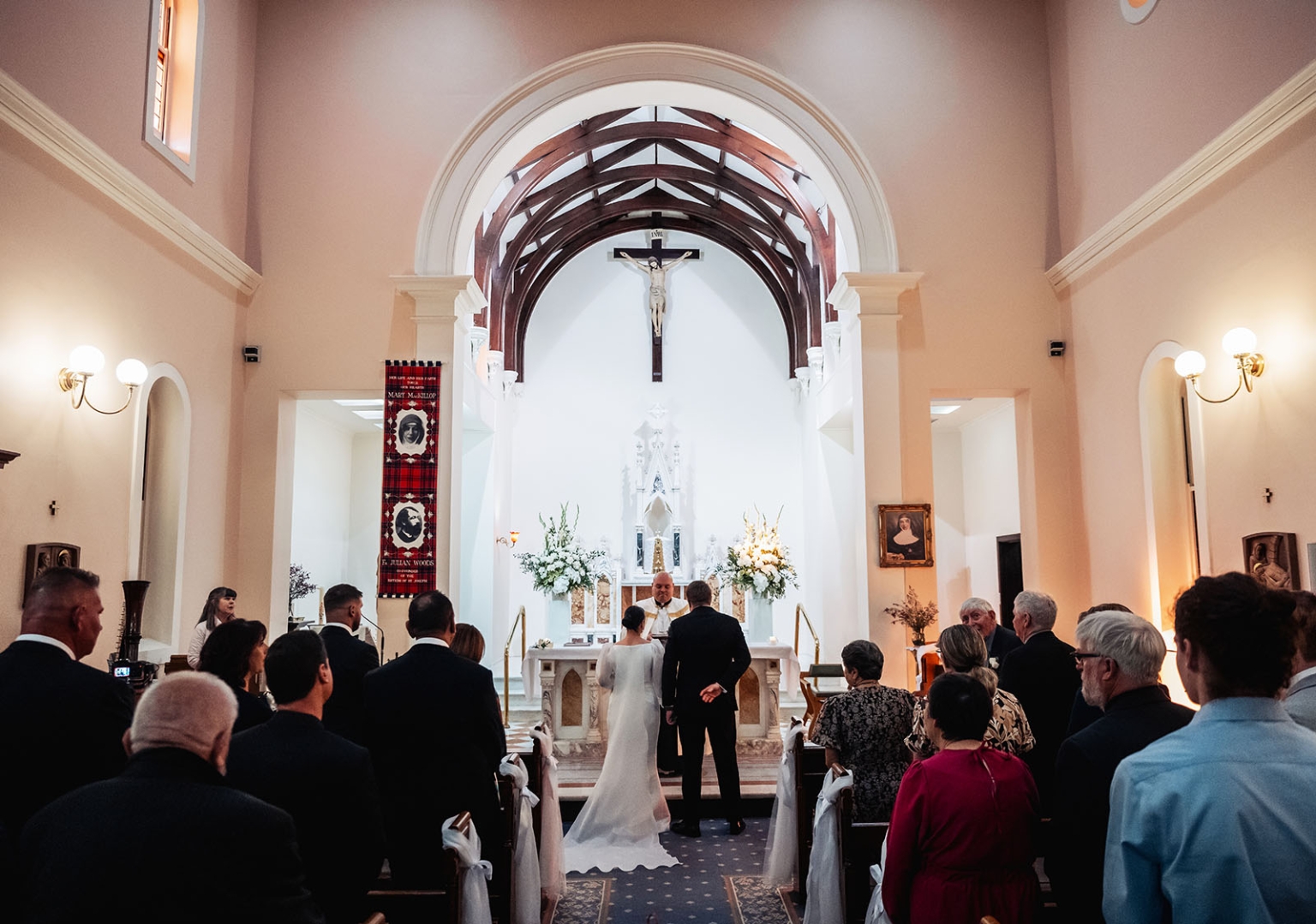 st joseph's chapel wedding – diana & michael 11 Diana and Michael standing before the altar during their wedding ceremony at St Joseph's Chapel, with guests seated in the pews.