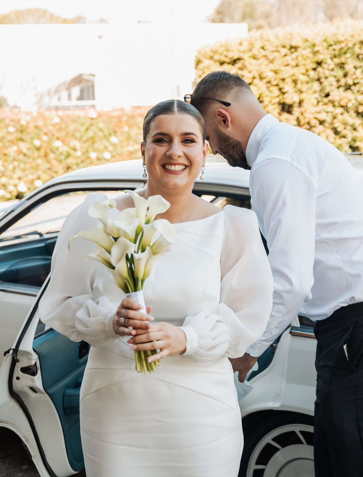 st joseph's chapel wedding – diana & michael 7 Diana holding white calla lilies beside a white vintage car as Michael stands by the open door