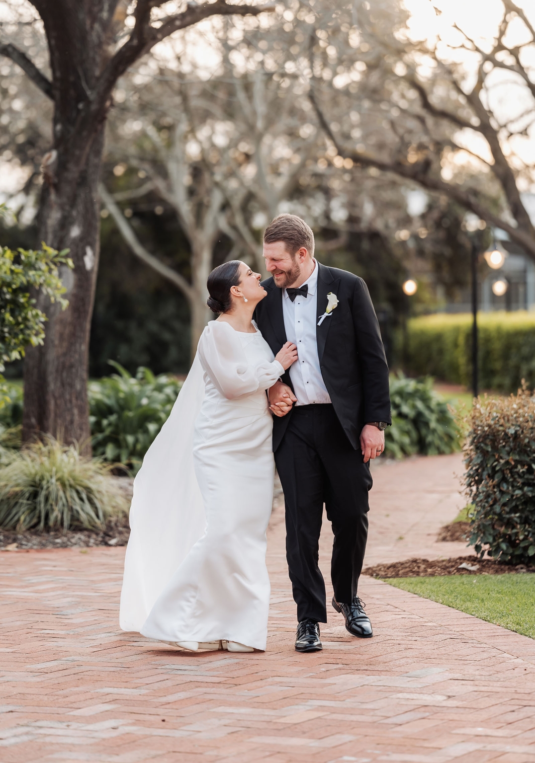 st joseph's chapel wedding – diana & michael 33 Diana and Michael walking hand in hand along a brick garden path in wedding attire