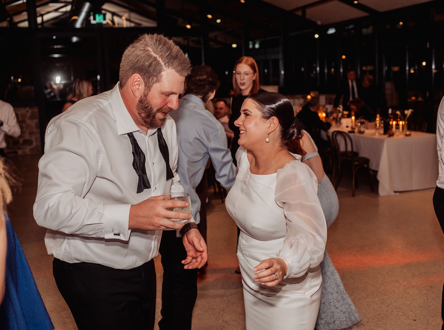 st joseph's chapel wedding – diana & michael 55 Diana and Michael smiling as they dance together at their wedding reception, with guests seated behind them.