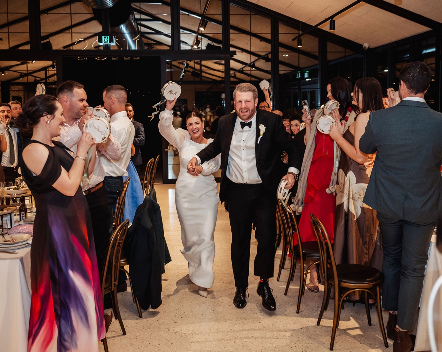 st joseph's chapel wedding – diana & michael 44 Diana and Michael enter their wedding reception as guests shake tambourines beside the dining tables.
