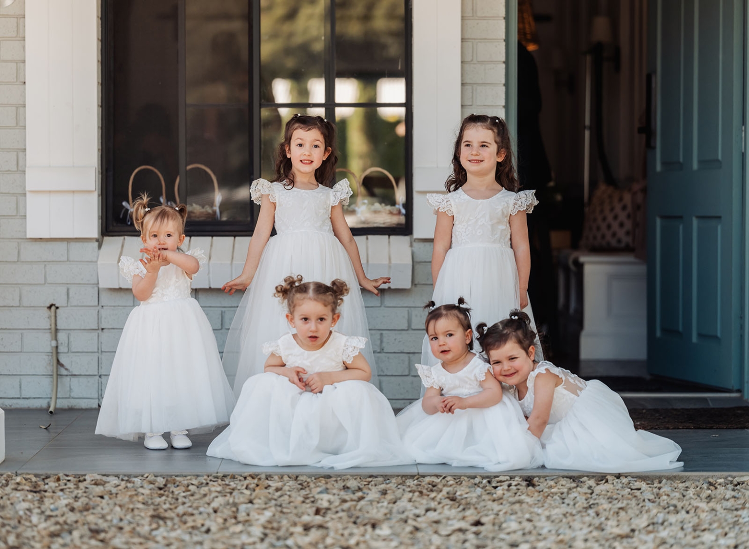 serafino winery wedding – maor & sasha 23 Six young flower girls in white dresses gathered on the front porch of a house