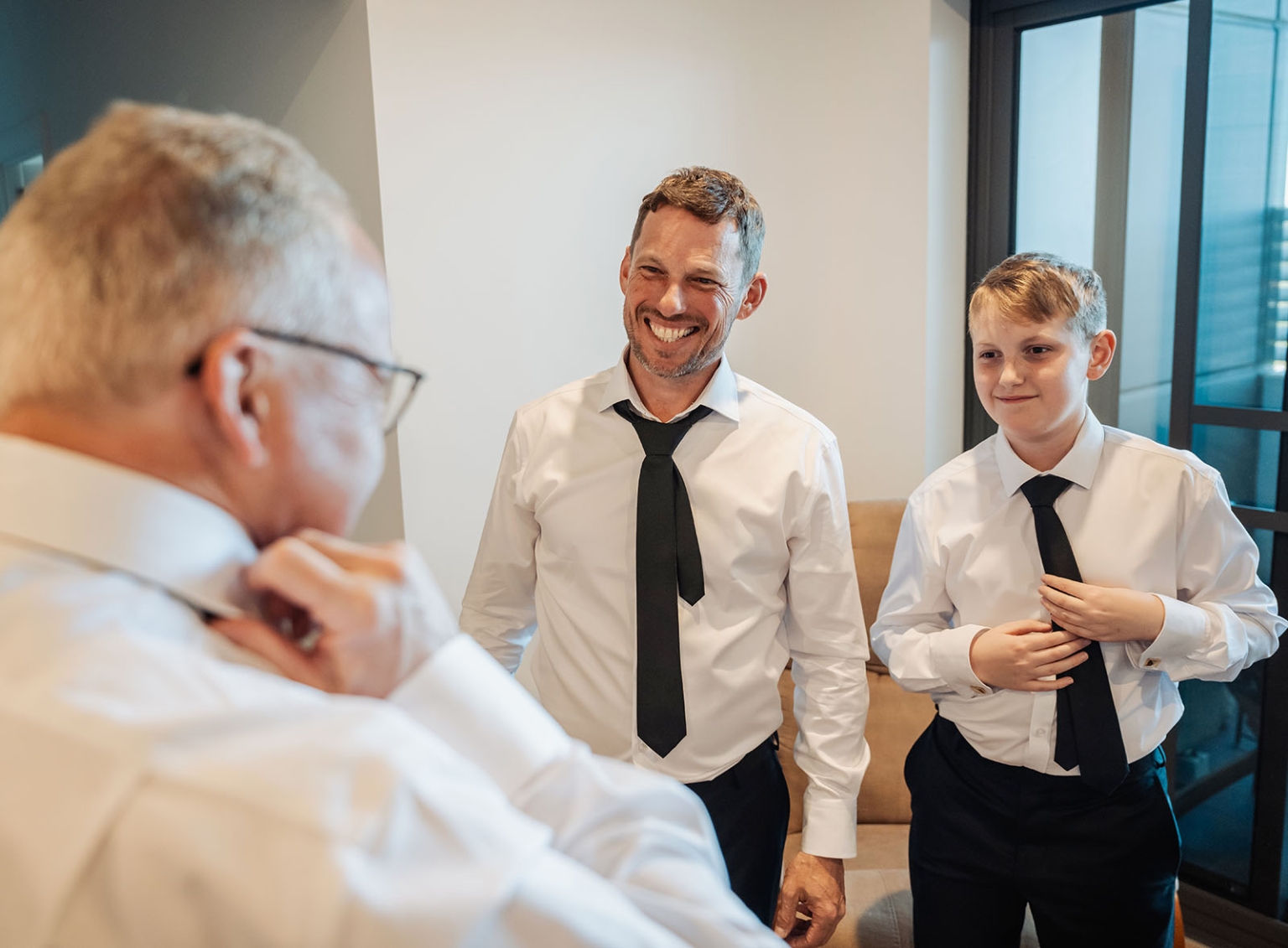 serafino winery wedding – maor & sasha 2 Three males in white shirts and black ties getting ready together in an apartment before a wedding