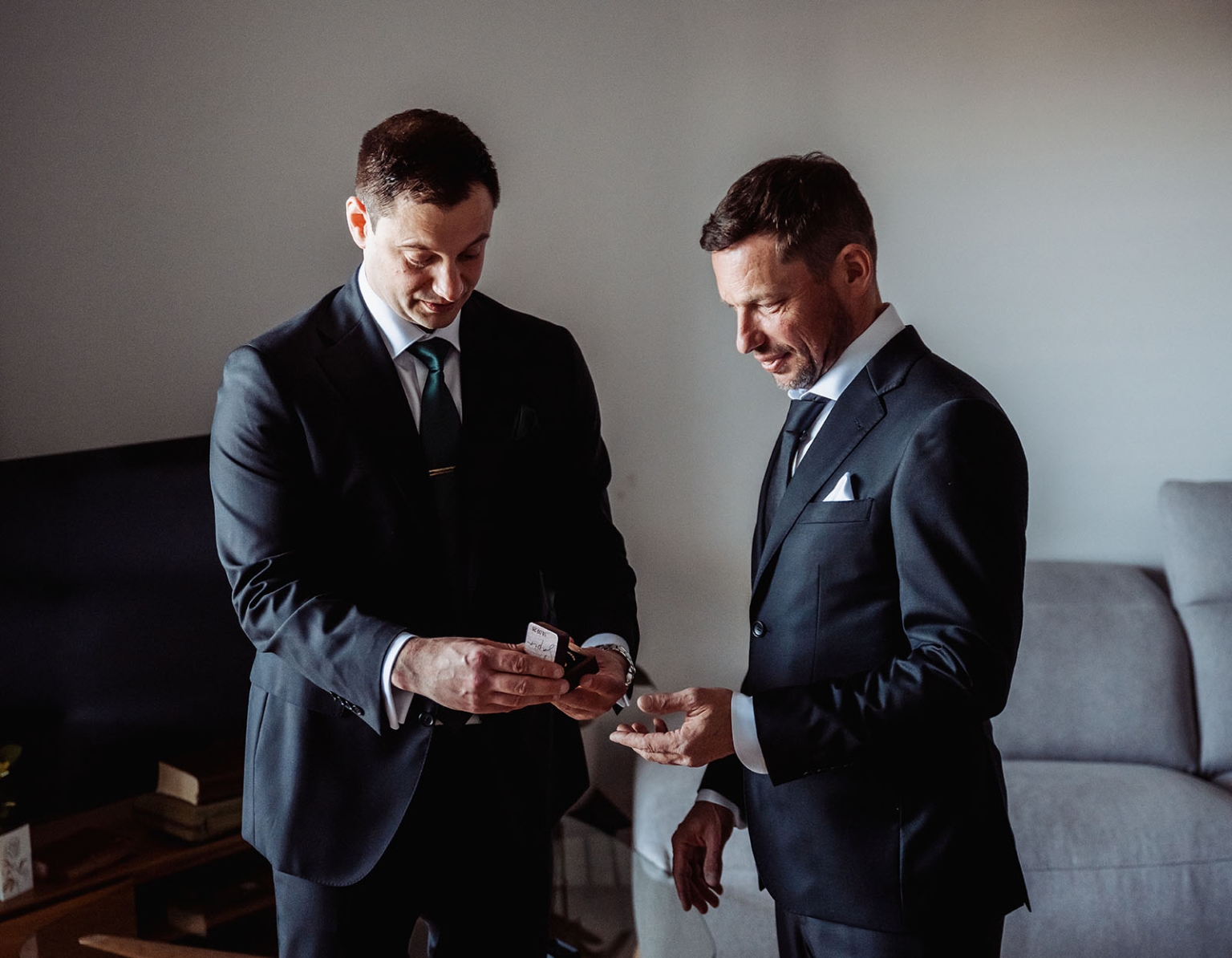 serafino winery wedding – maor & sasha 7 Two men in dark suits look at a small box while getting ready for a wedding in a Plympton apartment.