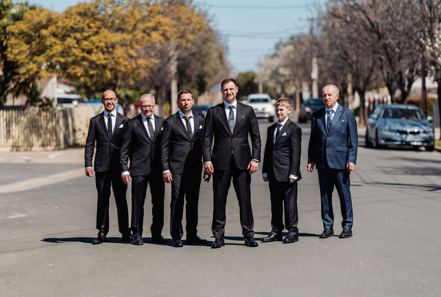 serafino winery wedding – maor & sasha 9 Groom and five groomsmen in dark suits standing on a tree-lined Plympton street before the wedding
