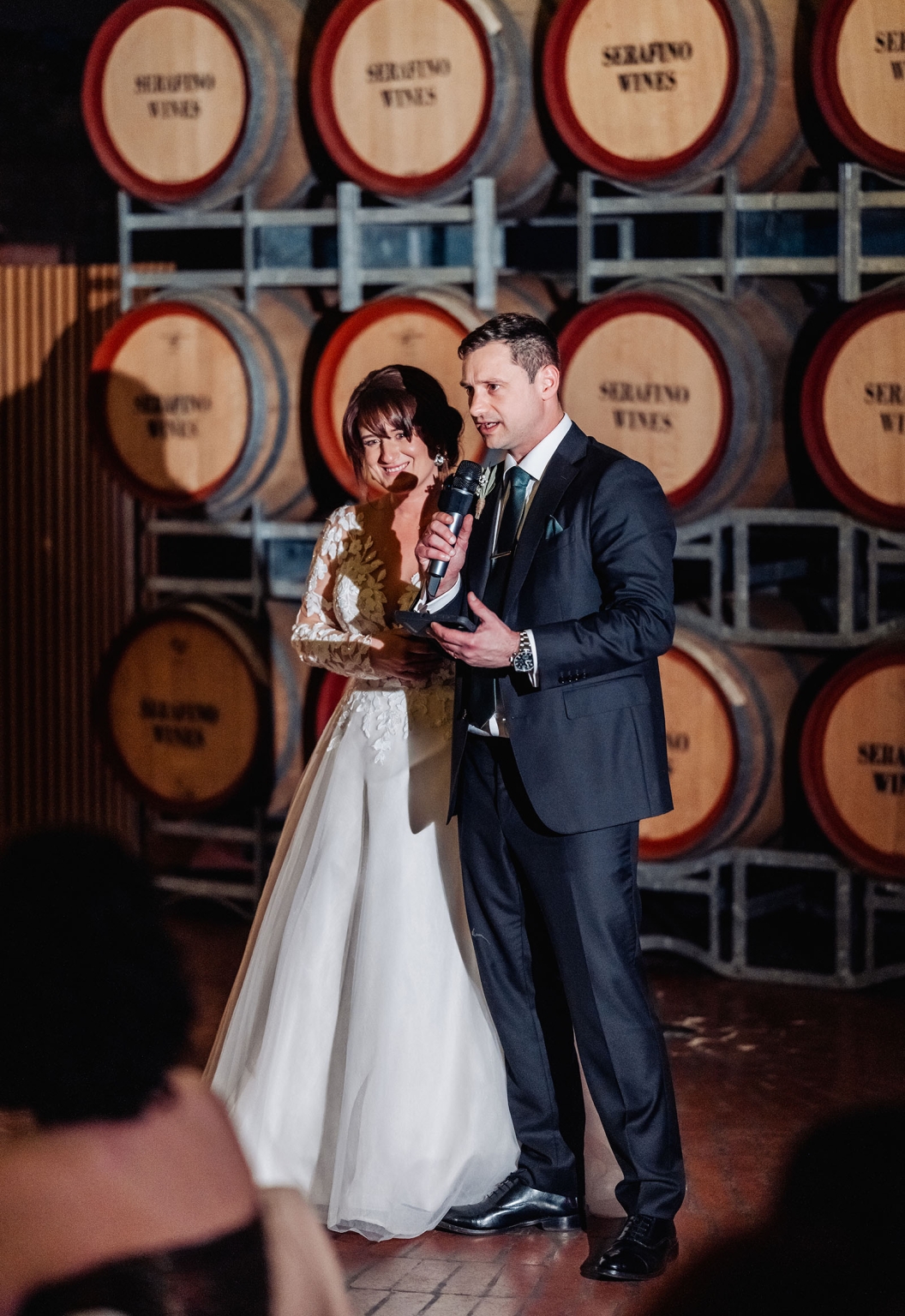 serafino winery wedding – maor & sasha 63 Groom giving a speech beside the bride in front of stacked Serafino wine barrels
