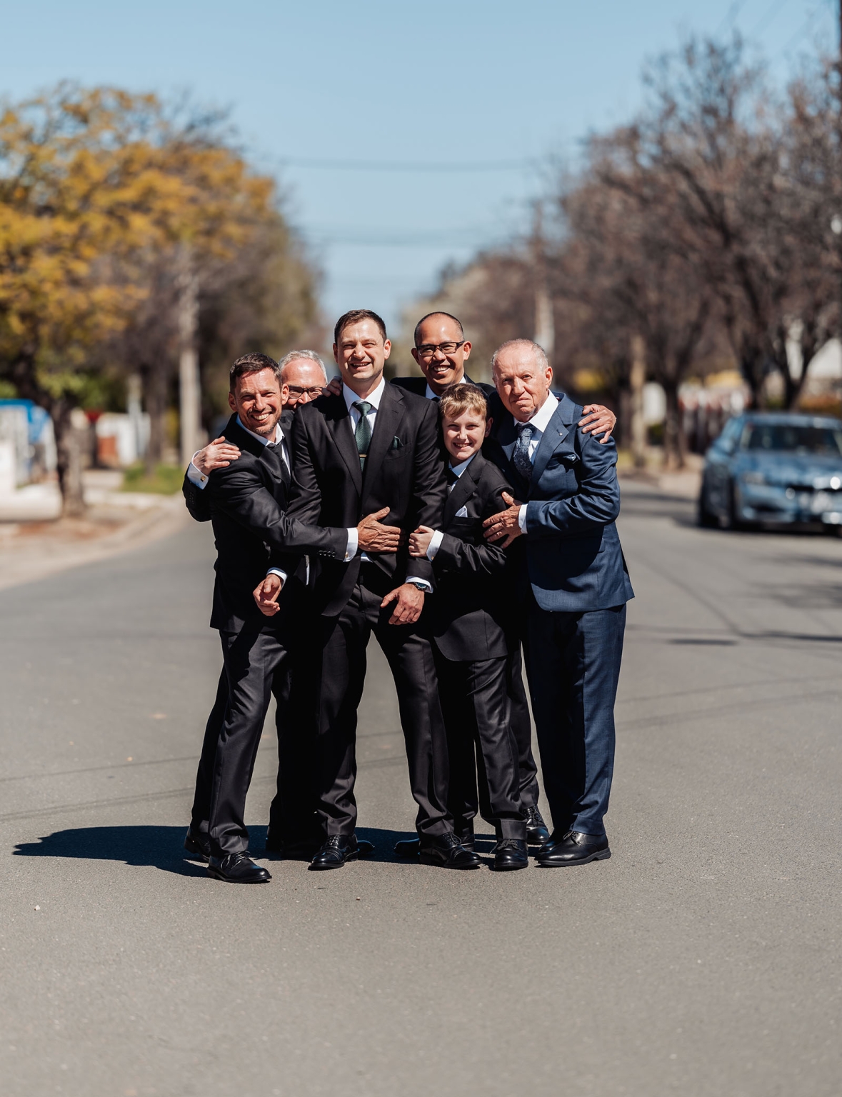 serafino winery wedding – maor & sasha 10 Groom and male wedding party smiling together on a tree-lined Plympton street in formal suits