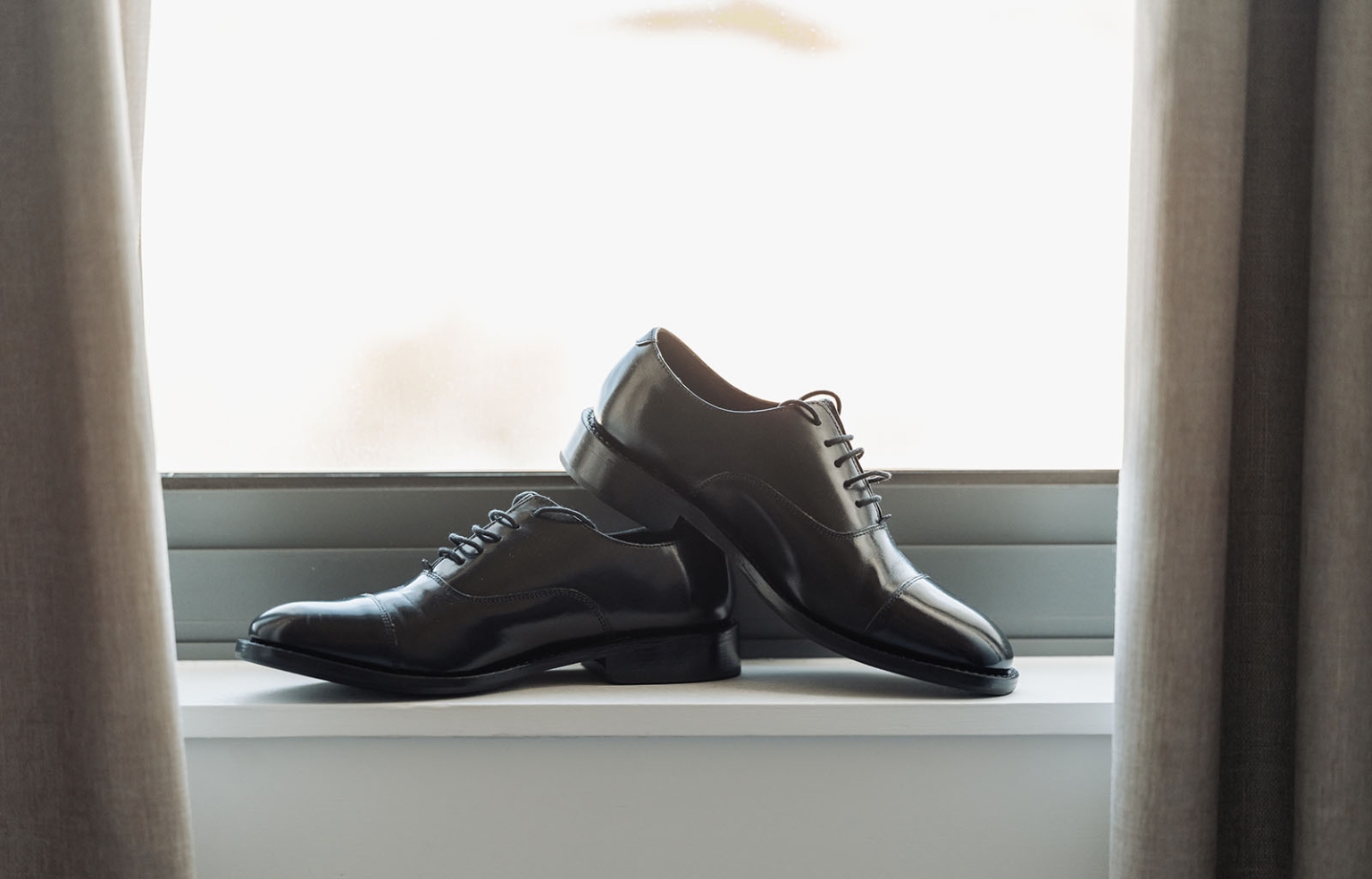 serafino winery wedding – maor & sasha 1 Pair of black leather lace-up wedding shoes arranged on a windowsill