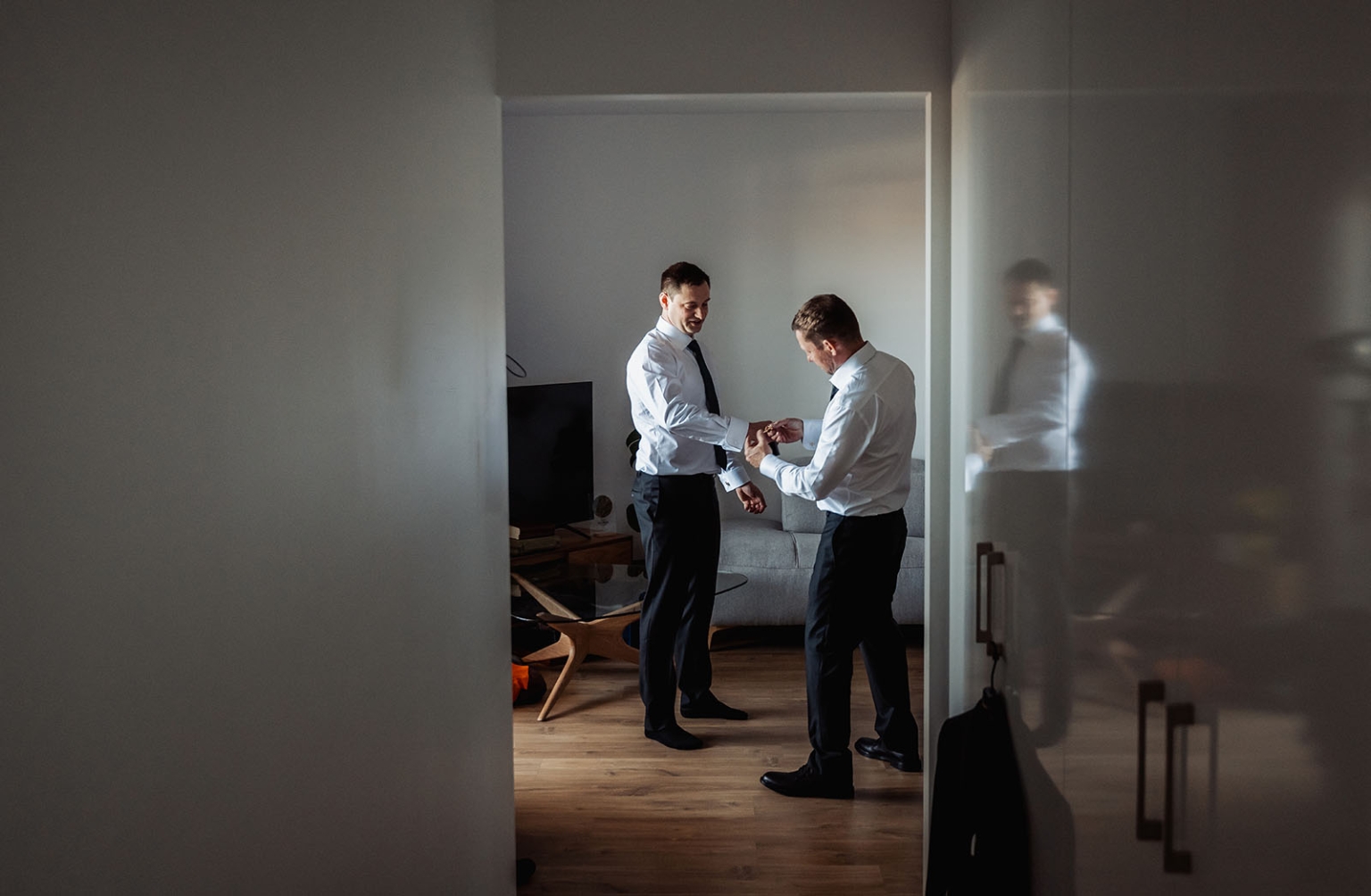 serafino winery wedding – maor & sasha 5 Two men in white shirts and black trousers adjust cufflinks while getting ready in a Plympton apartment.