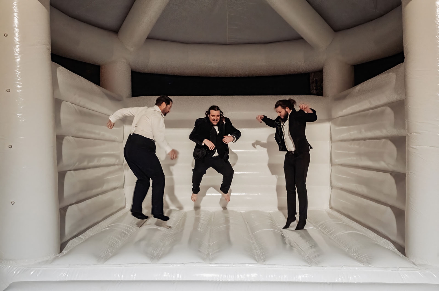 burbrook wedding – amber & angus | kuitpo forest wedding 56 Three formally dressed wedding guests jumping inside a large white inflatable bouncy castle.