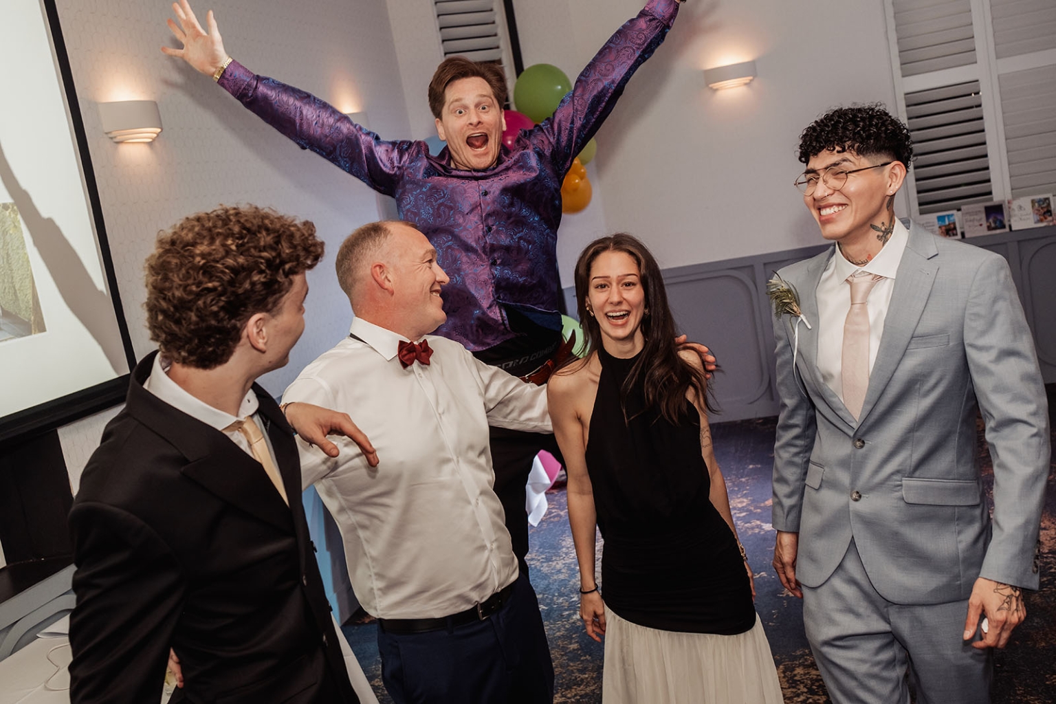 hotel royal wedding - brad & manuel 36 Five wedding guests laughing and celebrating together indoors, with one man raising his arms in excitement