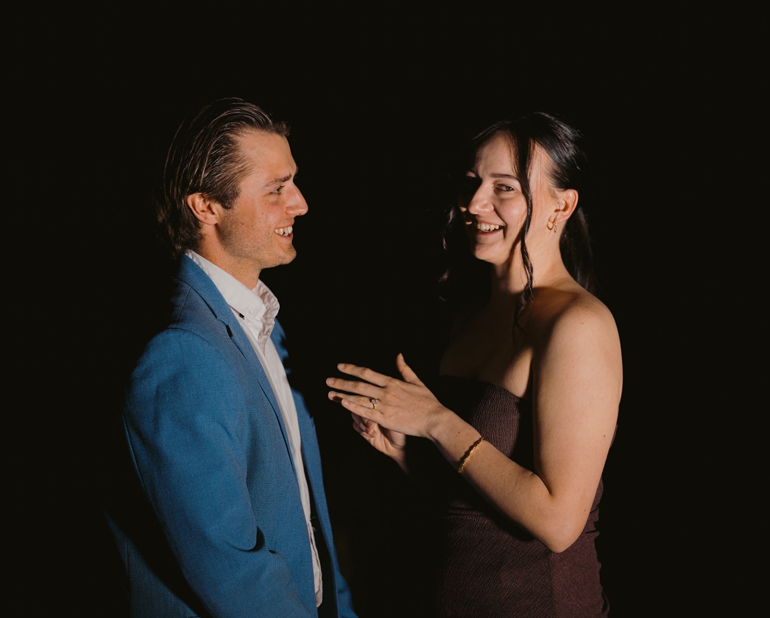 Kelly and Josh laughing together at night as she shows her engagement ring