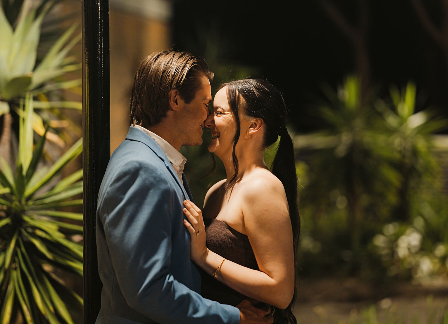 Kelly and Josh smiling together beside a window at Windy Point Restaurant, with her hand resting on his chest.