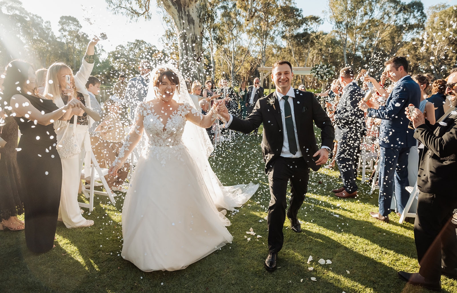 serafino winery wedding – maor & sasha 35 Maor and Sasha walk hand in hand through guests throwing white confetti after their outdoor wedding ceremony at Serafino Winery.
