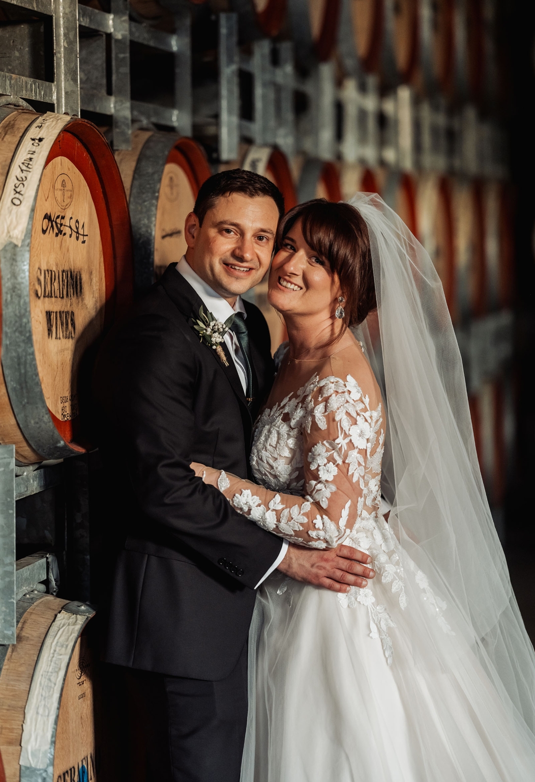 serafino winery wedding – maor & sasha 56 Maor and Sasha embracing beside stacked wine barrels at Serafino Winery