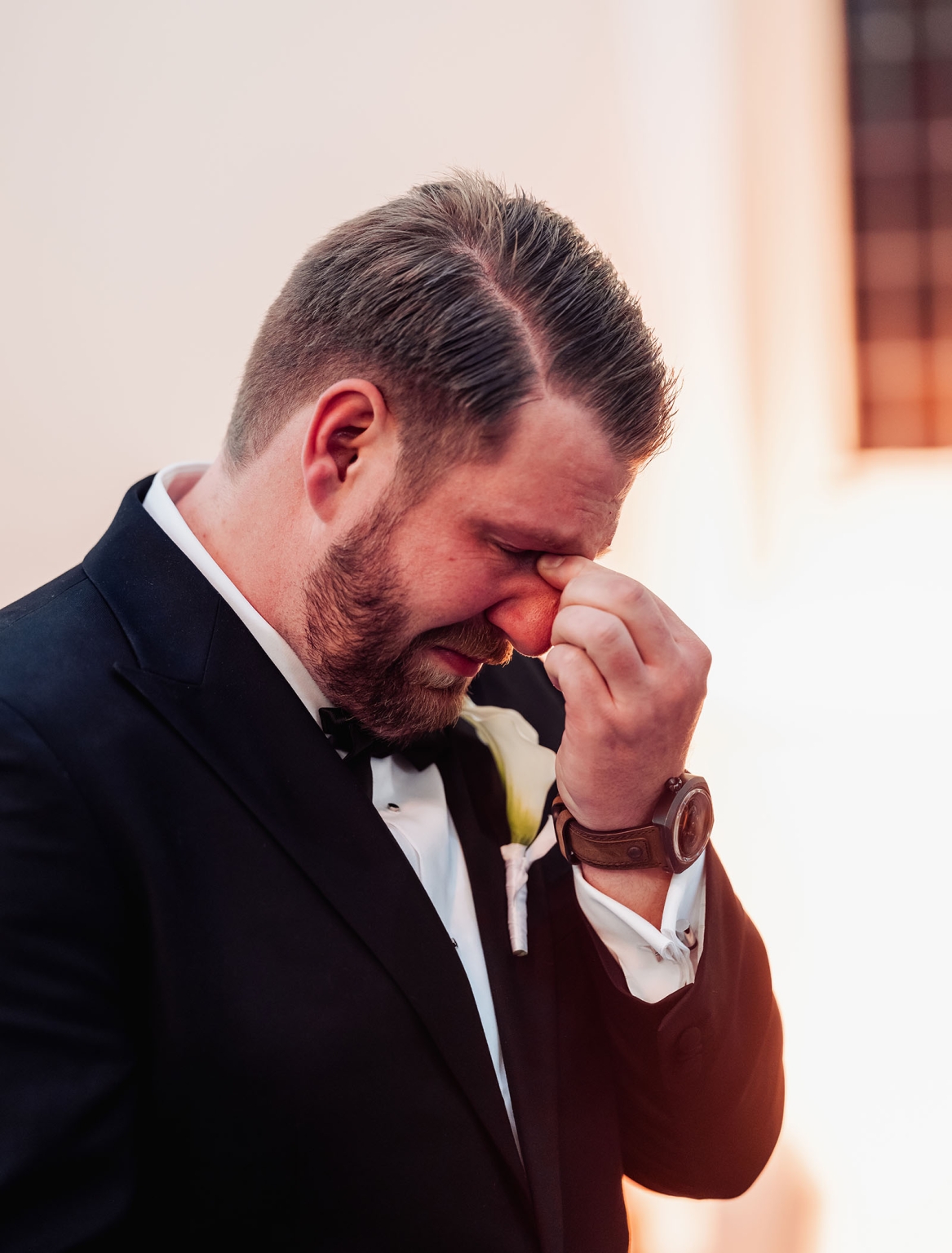 st joseph's chapel wedding – diana & michael 10 Groom in a black tuxedo and bow tie wiping his eye outside St Joseph's Chapel