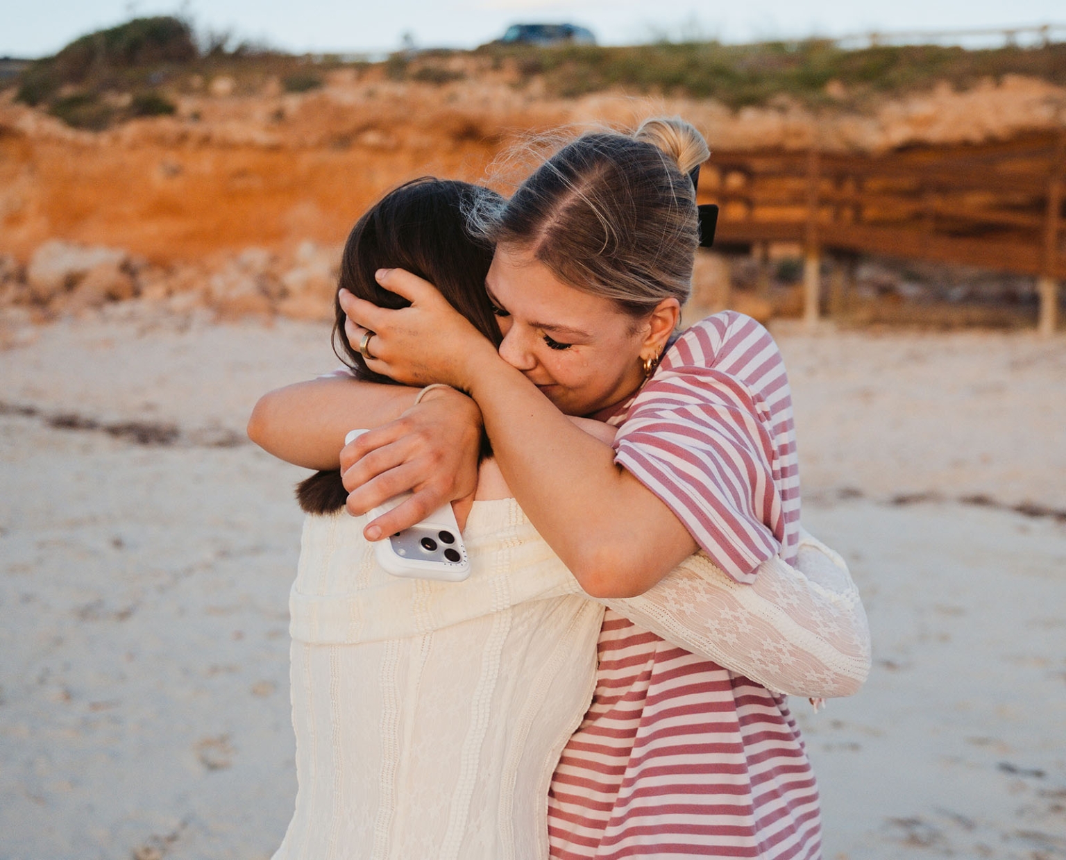 moonta's simms cove proposal – zoe & nathan 8 Two women share an emotional embrace on the sand at Simms Cove, Moonta.