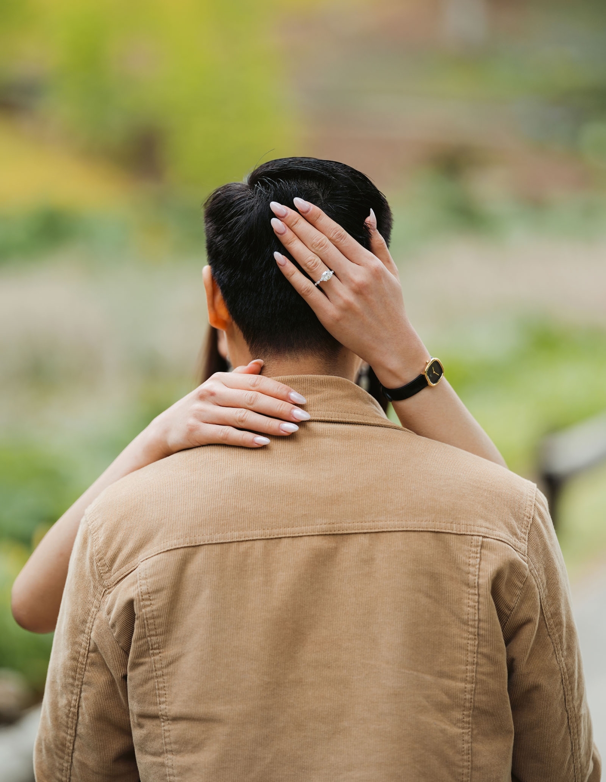 mt lofty botanic park proposal – watay & phouthun 9 Engaged woman wearing a diamond ring embraces her partner from behind at Mount Lofty Botanic Garden.