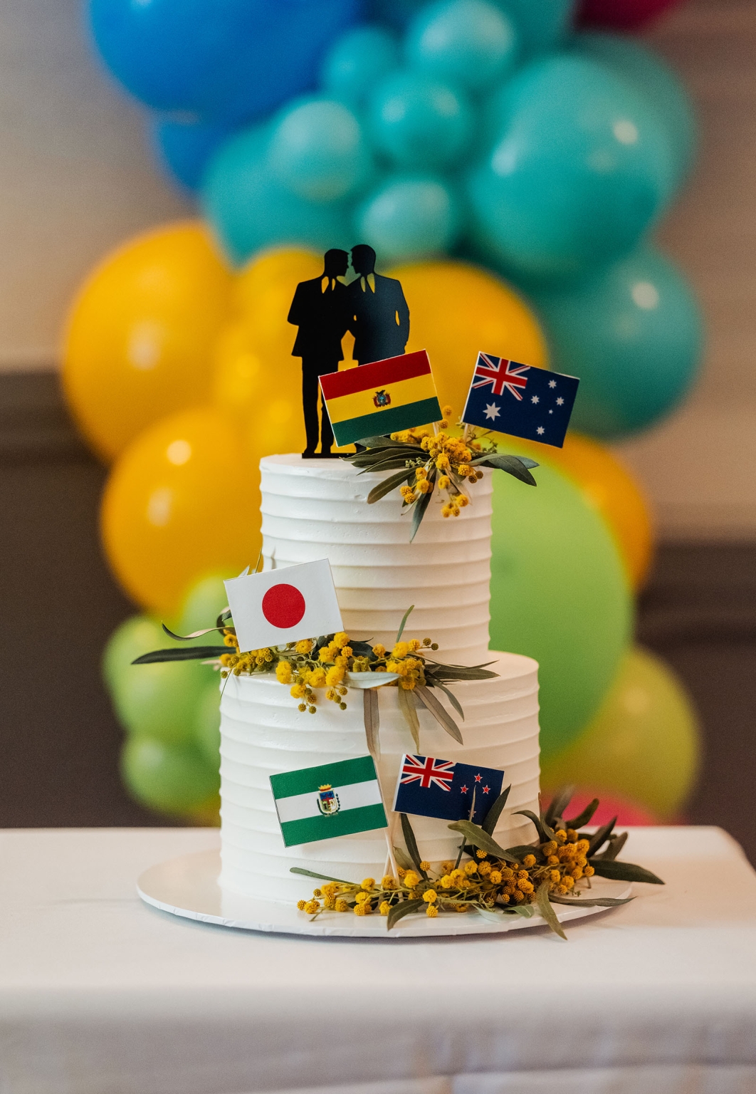 hotel royal wedding - brad & manuel 39 Three-tier white wedding cake with a groom couple topper, international flags and yellow flowers