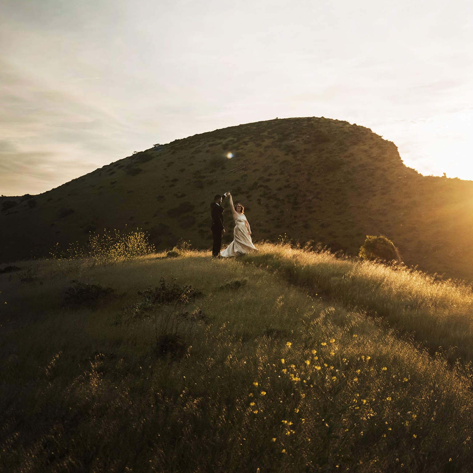Ebony and Punit dancing on a grassy hillside at sunset during their Second Valley wedding shoot
