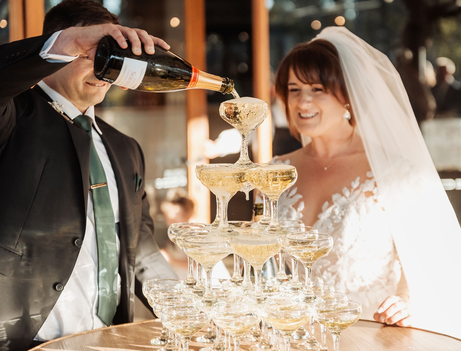 serafino winery wedding – maor & sasha 39 Groom pours sparkling wine into a champagne tower as the smiling bride watches at Serafino Winery.